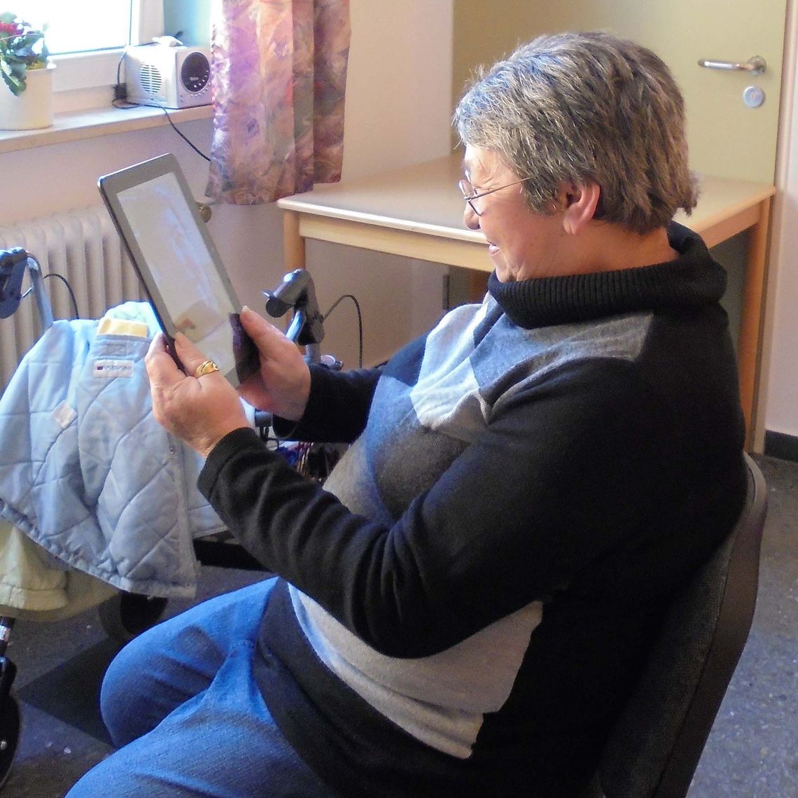 Das Bild zeigt eine Bewohnerin mit einem Tablet in den Händen