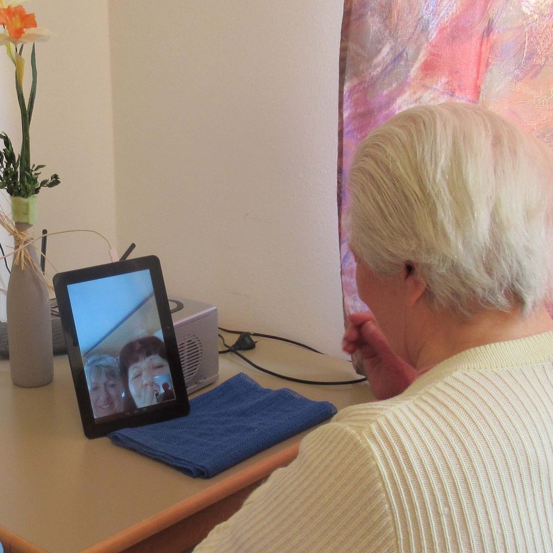 Das Bild zeigt eine Bewohnerin mit einem Tablet vor sich