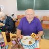 Das Bild zeigt einen Bewohner beim Weisswurst mit Laugenbrezel essen